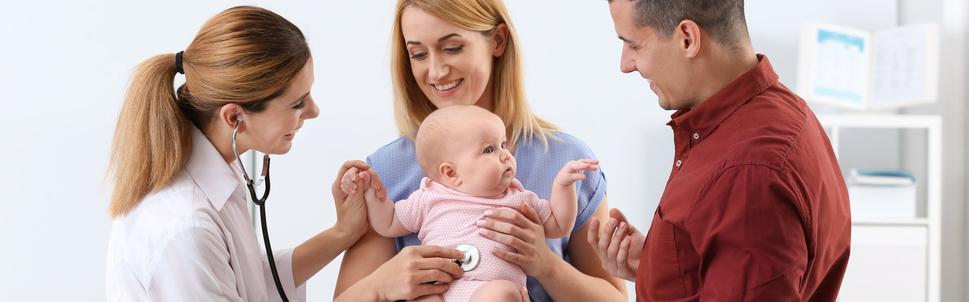 parents holding their baby while doctor is using the stethoscope