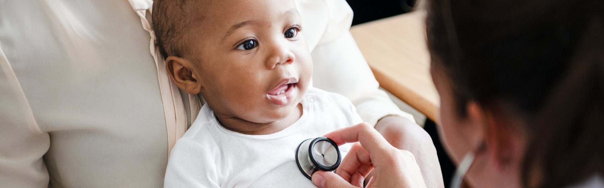 pediatrician checking the heartbeat of the infant